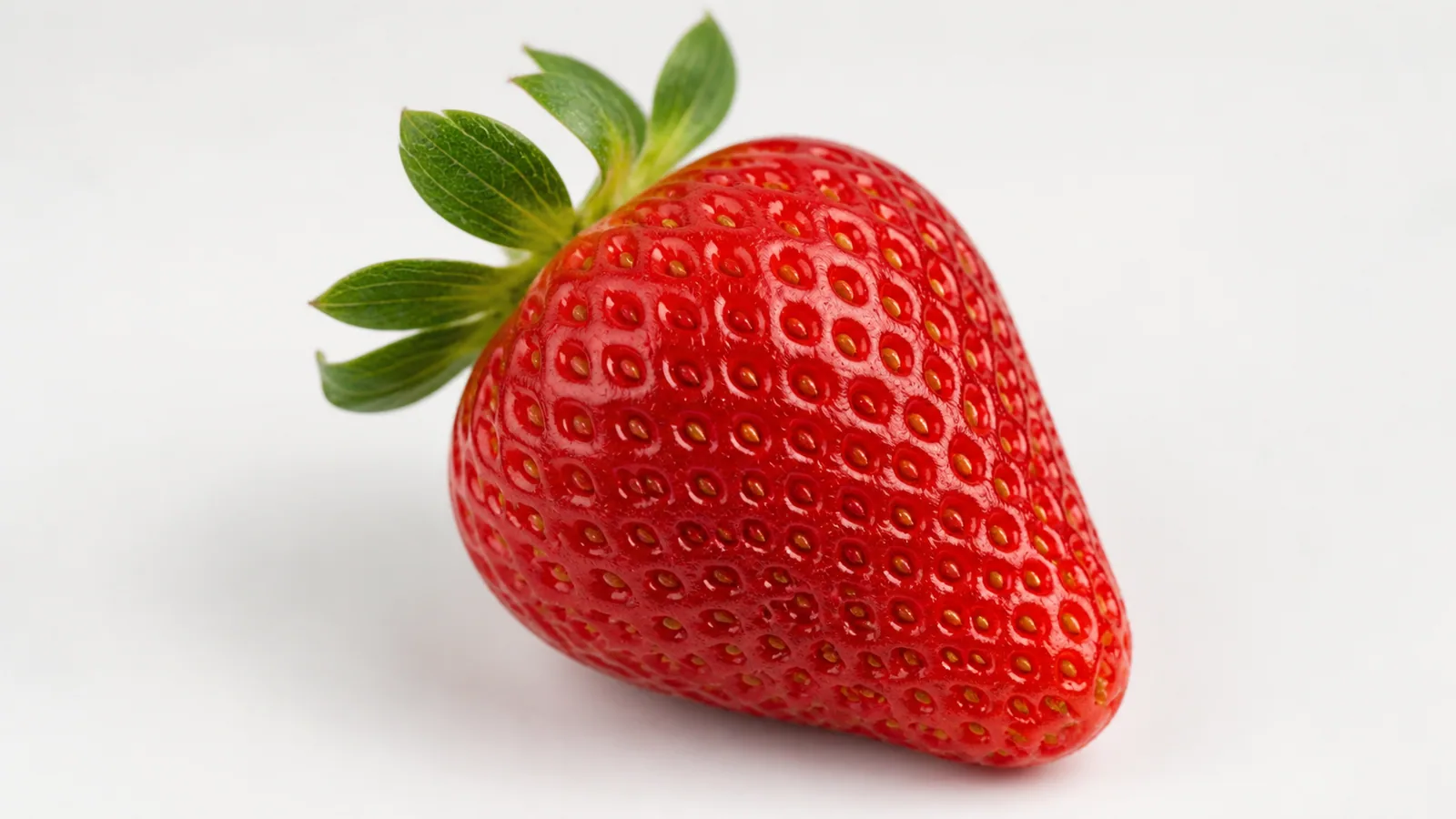 Photo-style teaching image of a ripe strawberry showing many small achenes on the red enlarged receptacle